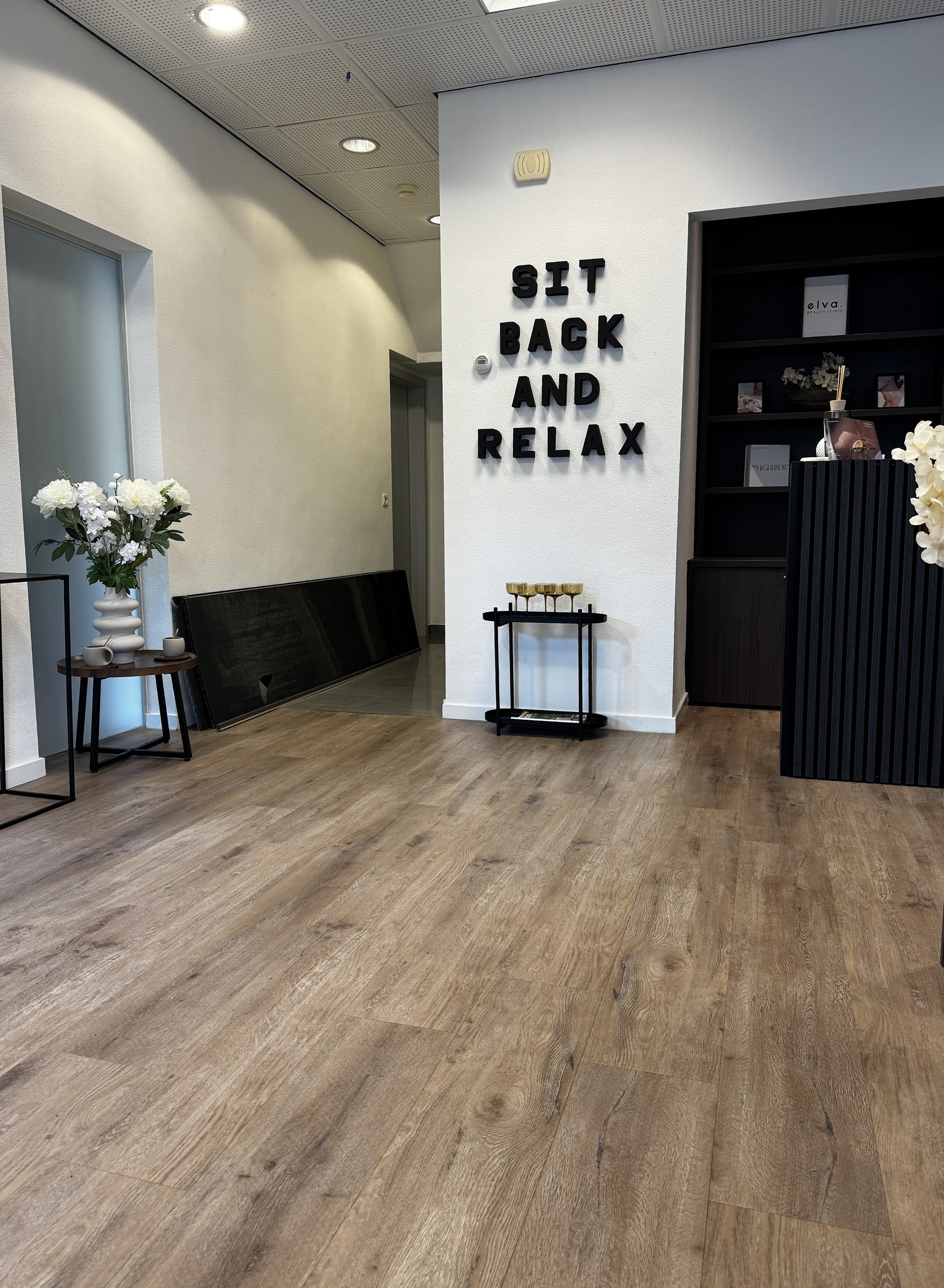 De gang van de salon met de tekst Sit back and relax op de muur